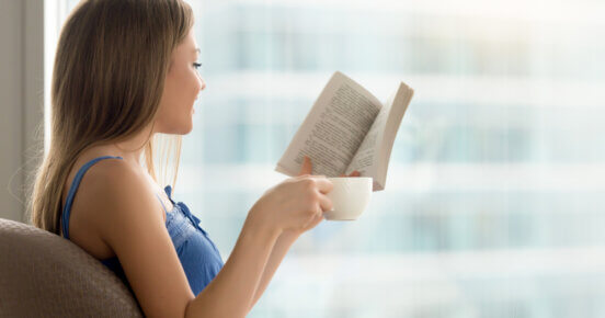 jovem mulher lendo livro de papel no cafe com cafe