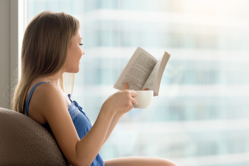 jovem mulher lendo livro de papel no cafe com cafe