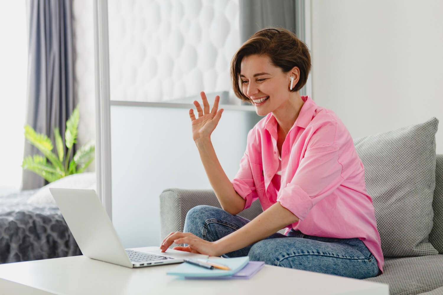 attractive smiling woman pink shirt sitting relaxed sofa home table working online laptop from home 1